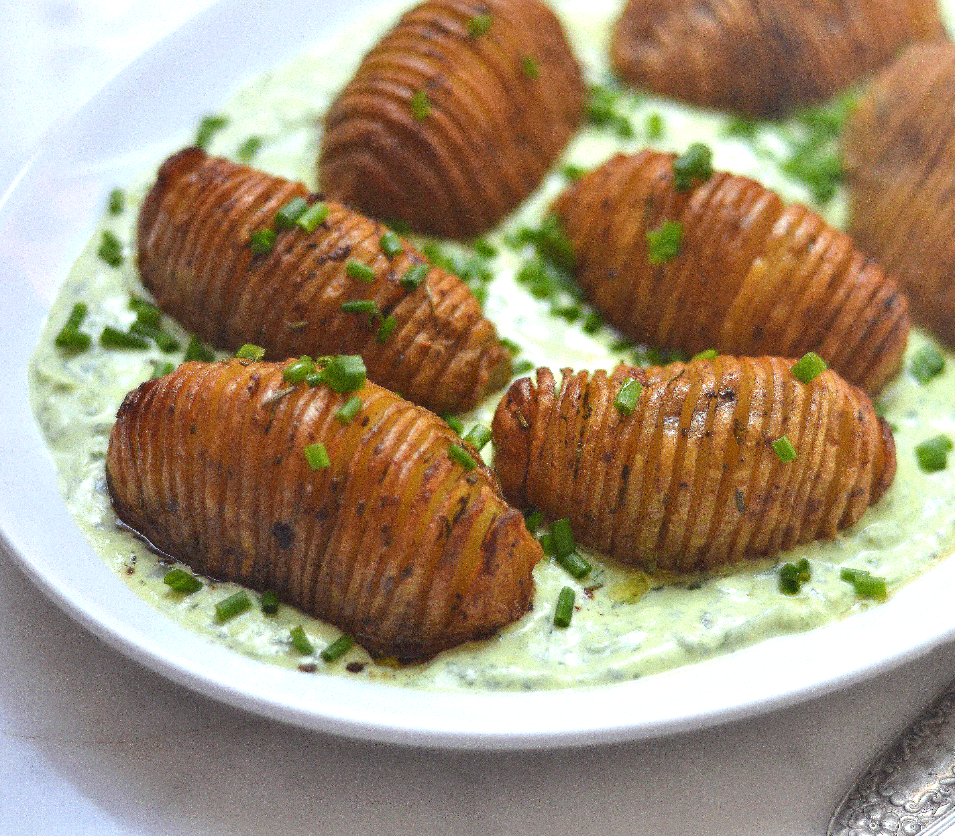 Papas hasselback con crema de queso y hierbas frescas